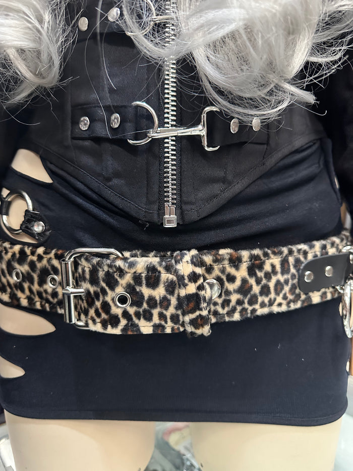 Person wearing a black jacket with a zipper and a leopard print belt.