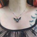 Silver colored zinc alloy bat wing necklace with silver crescent moon in center.
