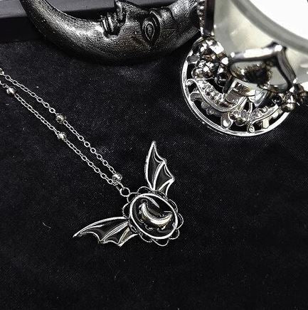 Silver colored zinc alloy bat wing necklace with silver crescent moon in center.