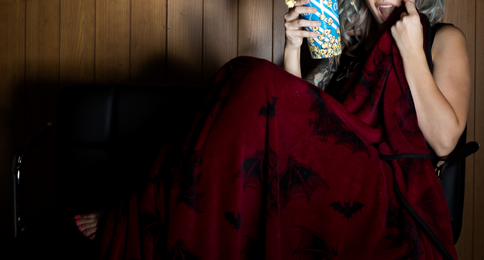 model with burgundy fleece blanket with black trim, featuring a black bats pattern.