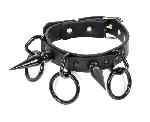 Black collar with large black D rings that have large black O rings hanging from them. Collar also has a black 3" spike on each side.