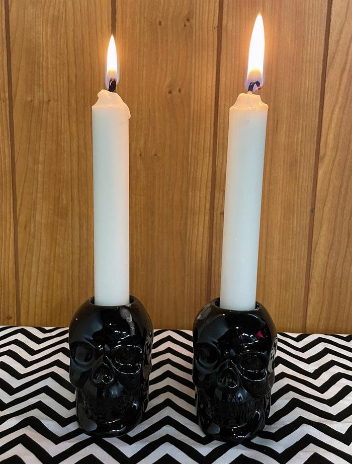 Black skull candlestick holders come in a set of two, and each holds a standard taper candle. CANDLES NOT INCLUDED.