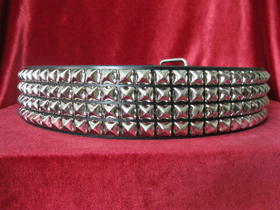 wide width black leather belt with four rows of silver pyramid studs. shows silver adjustable buckle