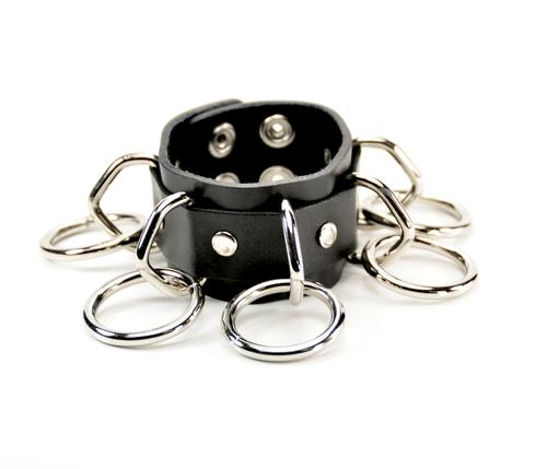black leather bracelet with five silver d rings with five hanging silver o rings attached. shows snap closure