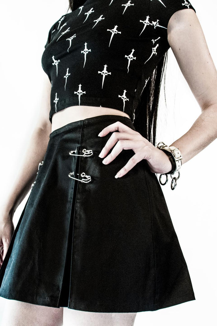 front of Black pleated skirt with front silver safety pin details.