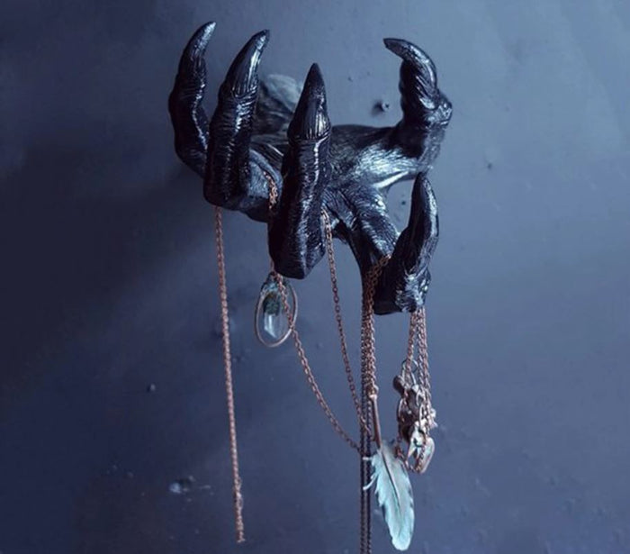 front view of Black witch hand statue with necklaces hanging from the fingers