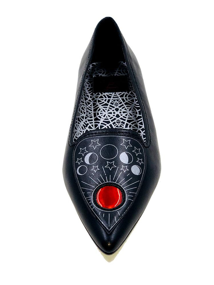 top of Black flats with pointy toe. Top of flats have silver Ouija board planchette print with red center. Inside sole of shoe is a black and white spiderweb-like pentagram print.