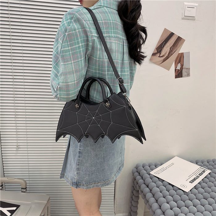 front side of purse showing White stitching spiderweb embroidery on front and hand straps. shown here being worn over the shoulder