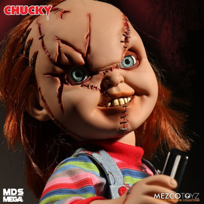 Close-up of a Chucky doll with red hair and striped shirt, holding a knife, against a dark background.