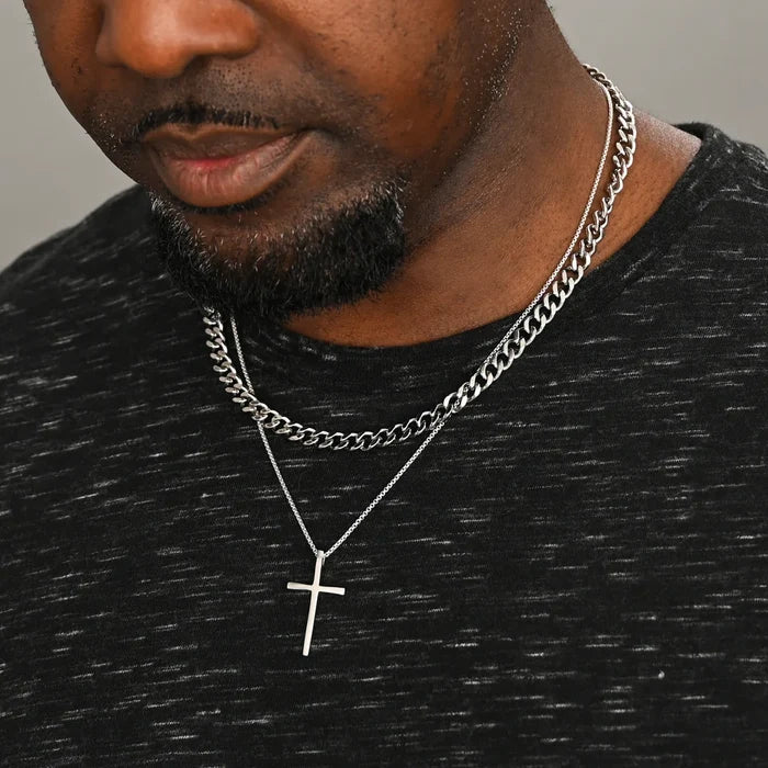 A man wearing the Classic Cross Necklace in Sterling Silver paired with another necklace in silver | Gifts against human trafficking