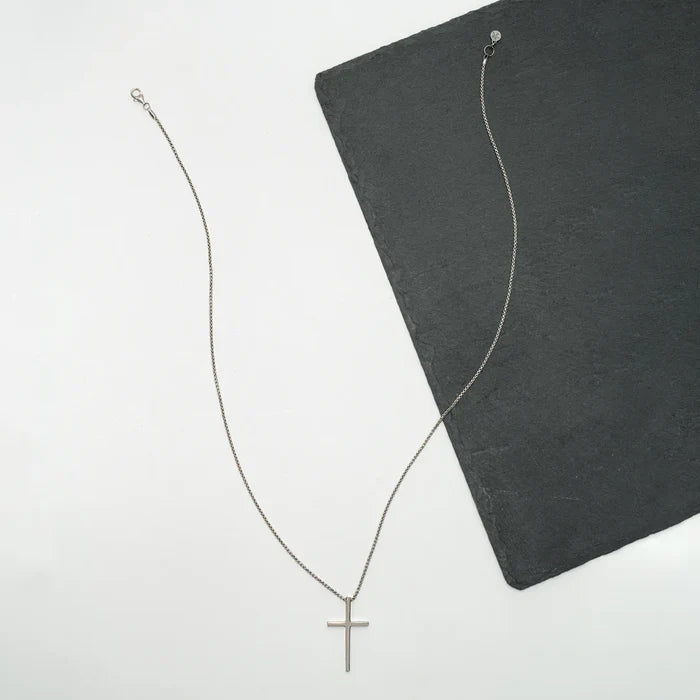 A laid out shot of the Classic Cross Necklace in Sterling Silver | Gifts against human trafficking