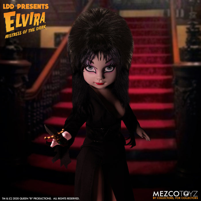 front view of Elvira Living Dead Doll, with iconic black dress and batty, teased hair, and comes with a dagger that she can store in her waist belt. Stands 10” tall and features 5 points of articulation. Packaged in window box for display.