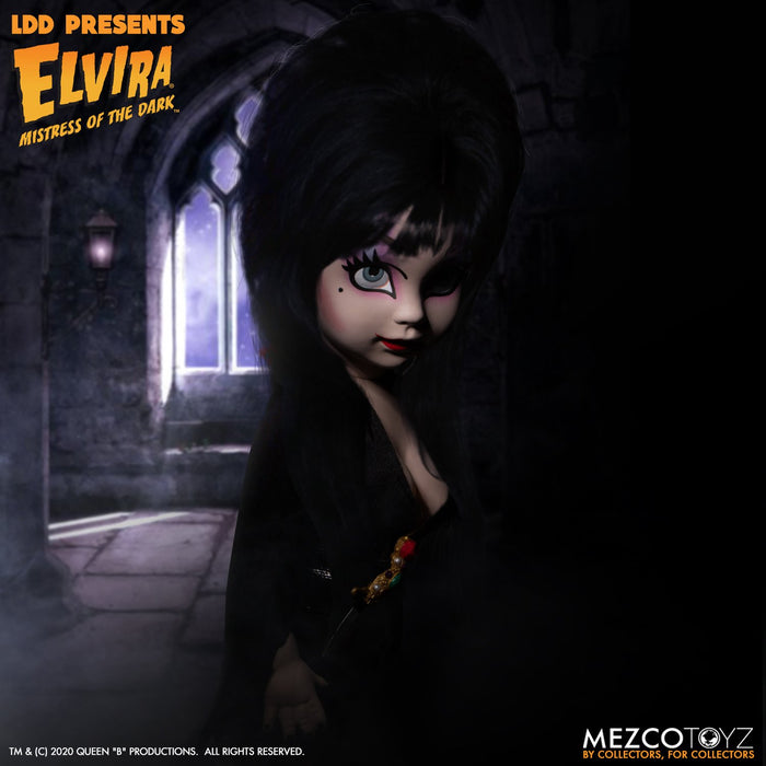 front side view of Elvira Living Dead Doll, with iconic black dress and batty, teased hair, and comes with a dagger that she can store in her waist belt. Stands 10” tall and features 5 points of articulation. Packaged in window box for display.