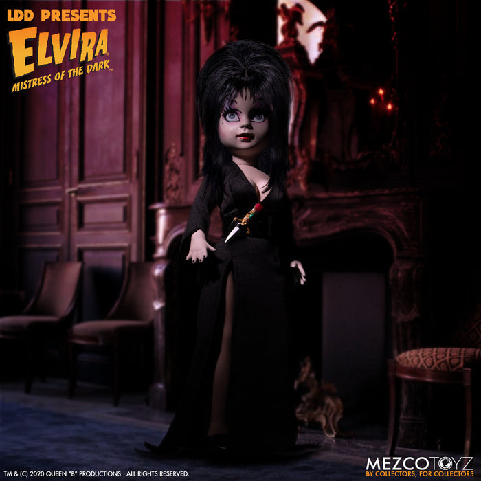 front view of Elvira Living Dead Doll, with iconic black dress and batty, teased hair, and comes with a dagger that she can store in her waist belt. Stands 10” tall and features 5 points of articulation. Packaged in window box for display.