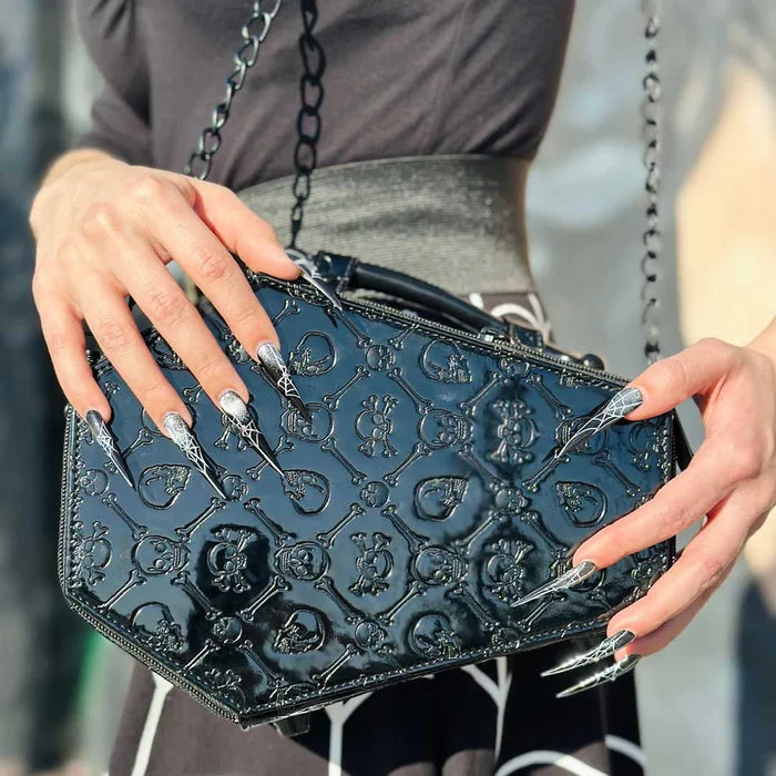 model with spider web fingernails holding bag