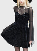 Model wearing a black dress with sheer sleeves and a black hat on a white background