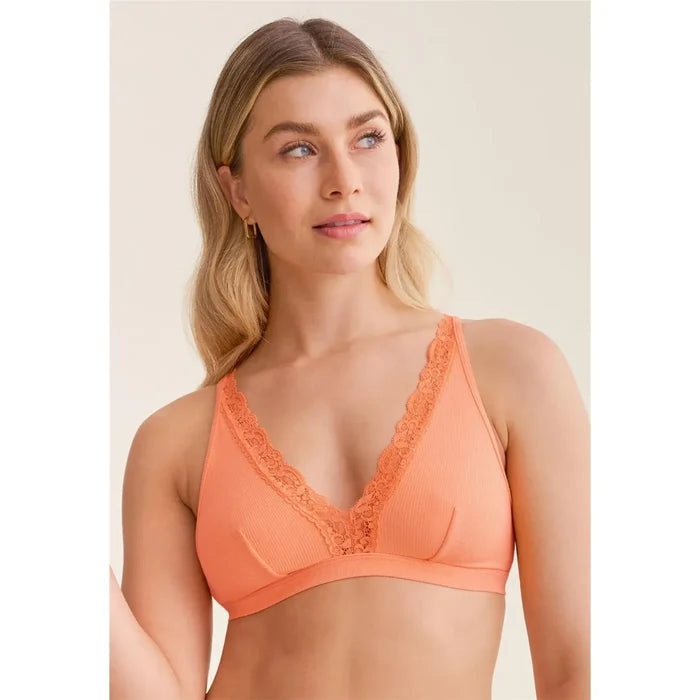 Woman wearing an orange bralette with lace details on a beige background