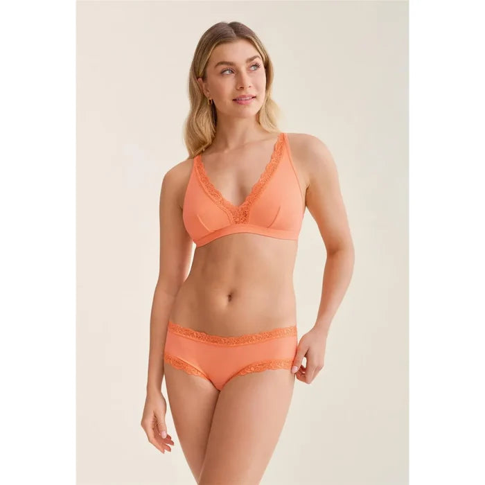 Woman wearing an orange lingerie set on a plain background