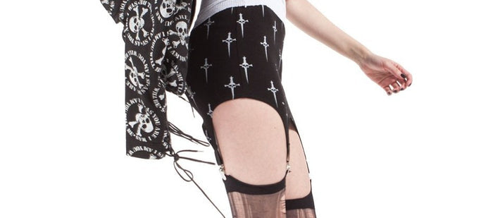 side of Black garter skirt with white all over print Lip Service classic dagger logo. Stockings not included.