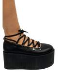 Black vegan leather upper, silver chrome hardware, black molded bottom. Top of Mary Jane laces up through D rings, and then ties around the ankle.