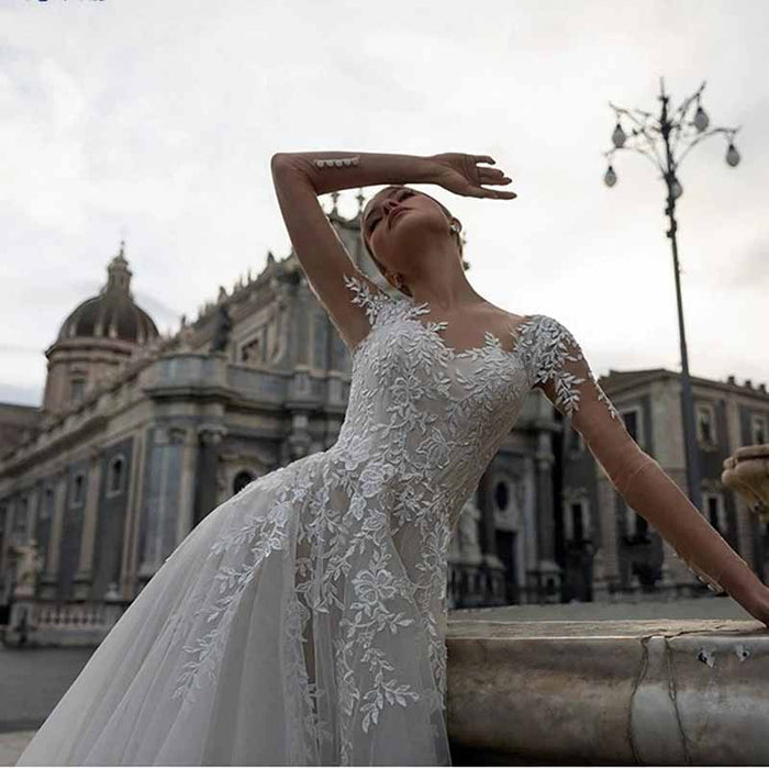 Elegant lace boho wedding dress with floral details on a model posing outdoors