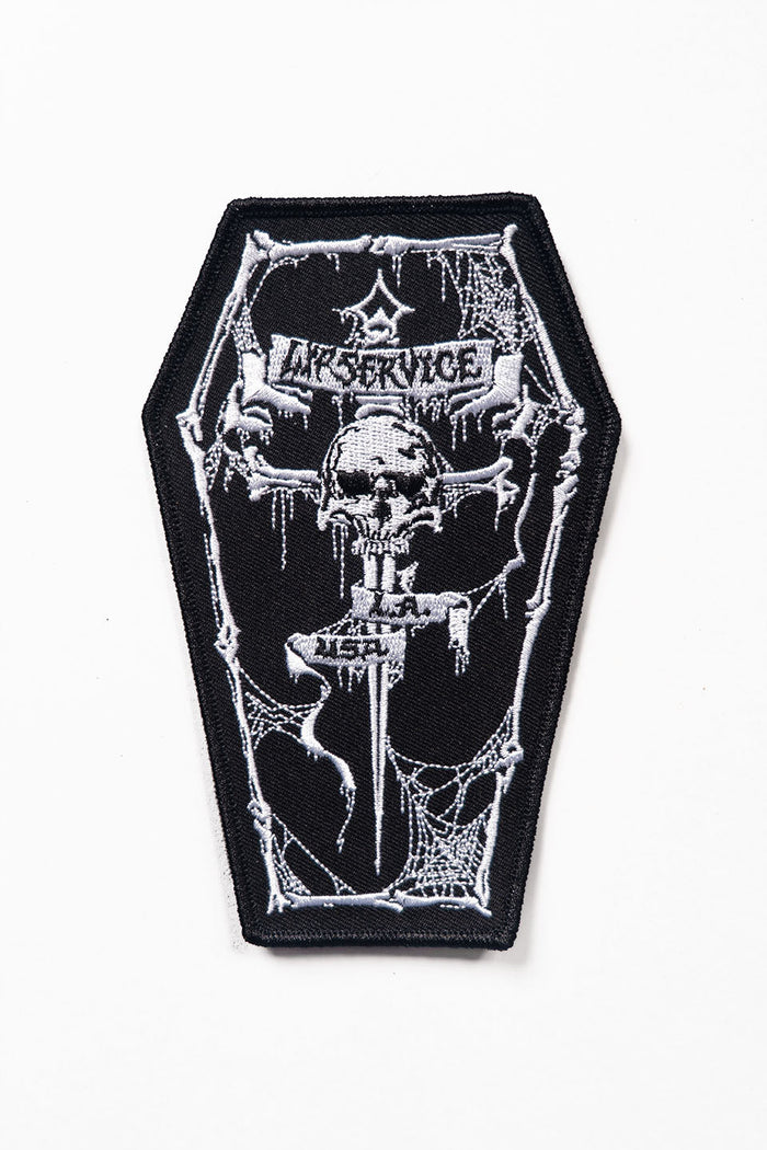 Black and white patch with a skull and coffin design on a white background