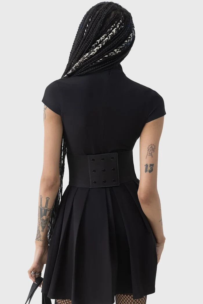 Person wearing a black dress with a belt on a white background