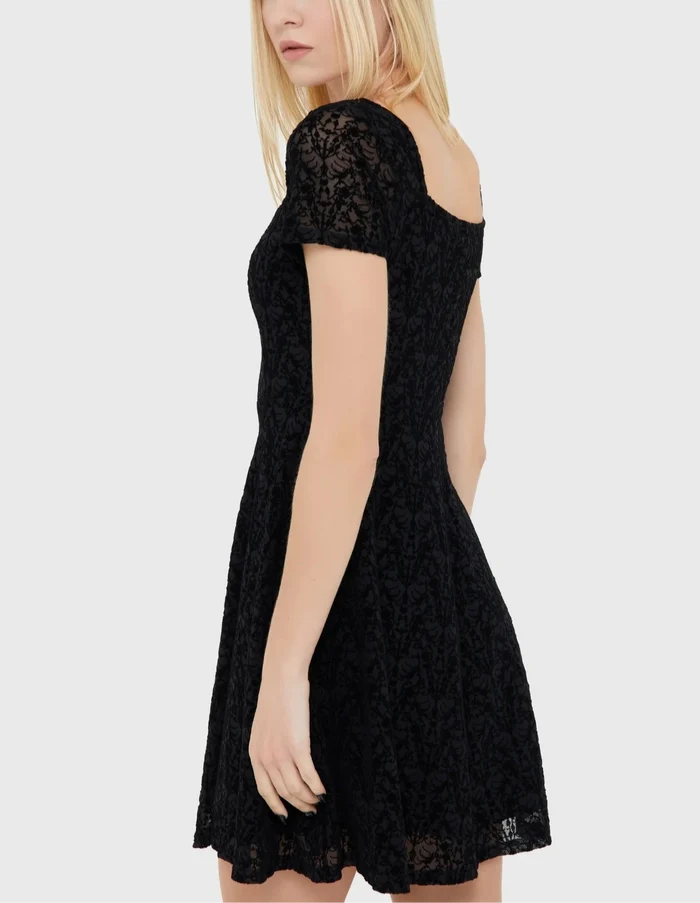 Model wearing a black lace dress on a white background