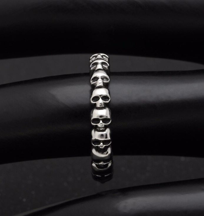 Silver band ring with multi-skull design.