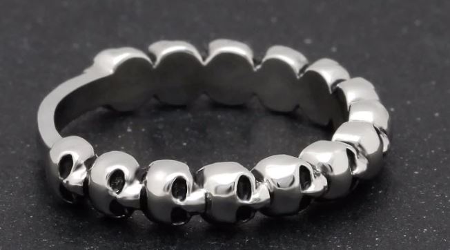 Silver band ring with multi-skull design.