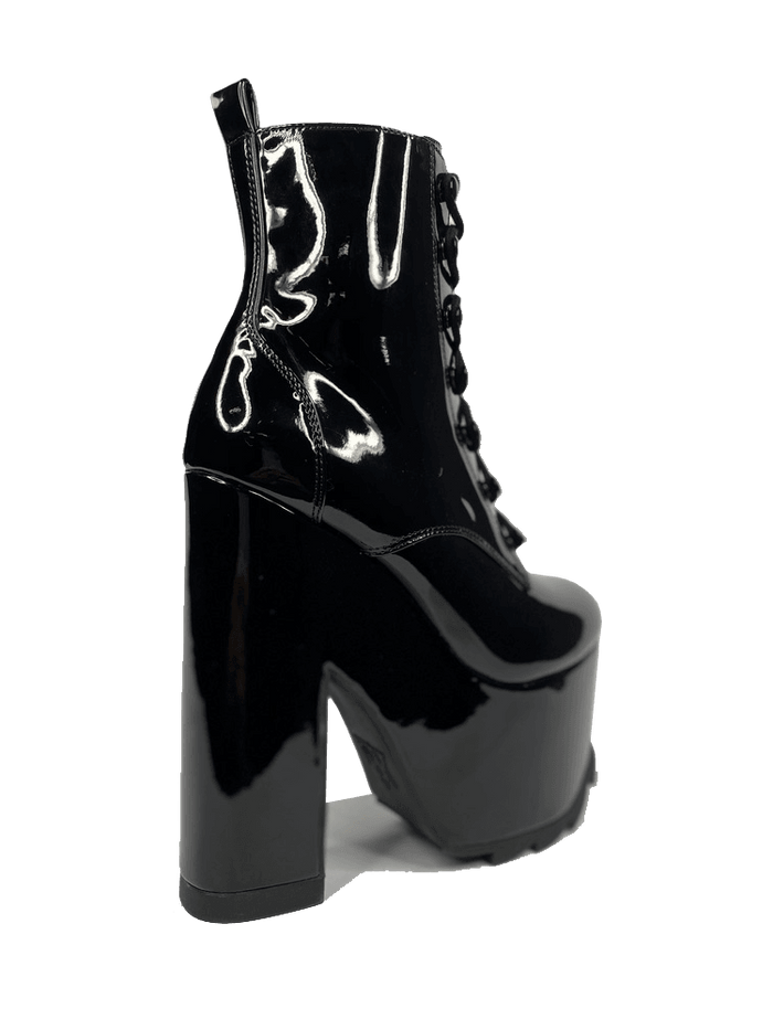 outer view of Black vegan shiny patent leather tall military style platform boot with black cotton laces and black inner zipper. Front of platform has a fanned grip for better stability when walking.
