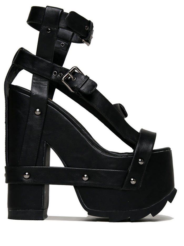 outer view of black vegan leather strappy platform sandal with 6.5" heel. Sandal has gunmetal hardware, adjustable ankle strap and adjustable side strap. Bottom of front platform has a fanned grip for better stability.