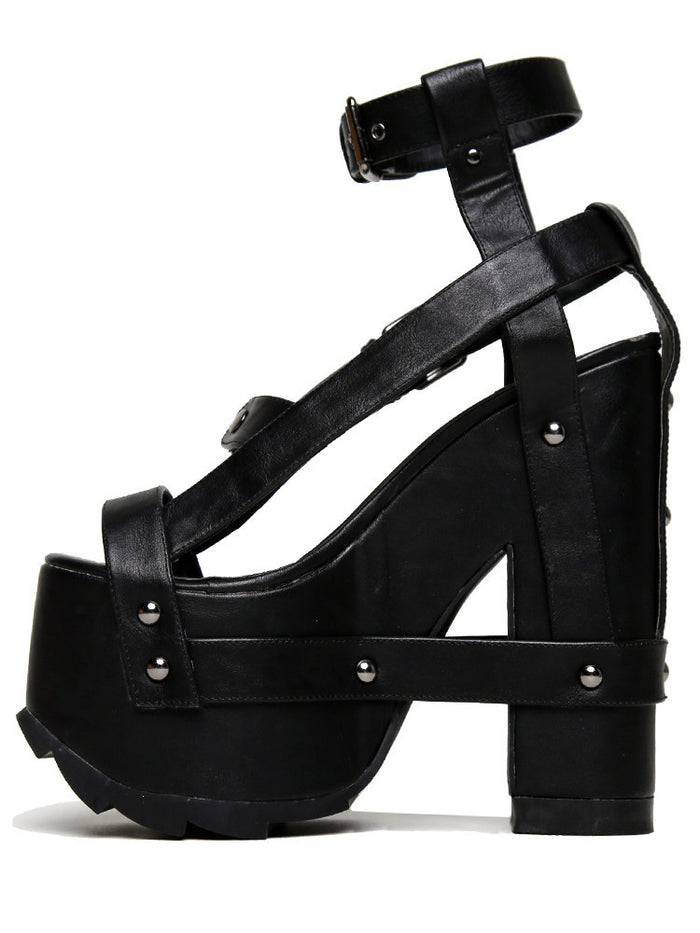 outer view of black vegan leather strappy platform sandal with 6.5" heel. Sandal has gunmetal hardware, adjustable ankle strap and adjustable side strap. Bottom of front platform has a fanned grip for better stability.