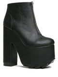 outer view of black vegan leather sleek 6.5" heel boot with silver front zip. Bottom of boot has a fanned front grip for better stability when walking.