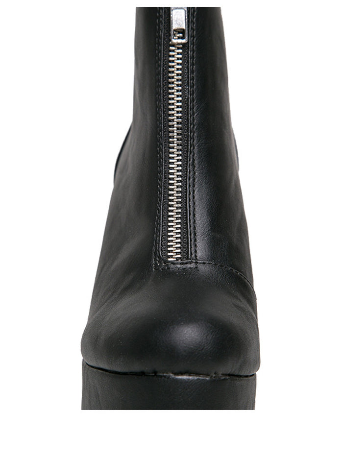 front view of black vegan leather sleek 6.5" heel boot with silver front zip. Bottom of boot has a fanned front grip for better stability when walking.