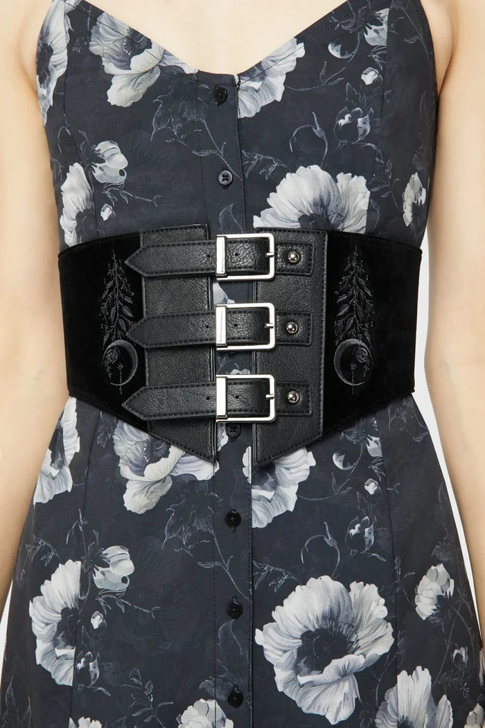Model wearing a floral pattern dress with black corset-style belt on top