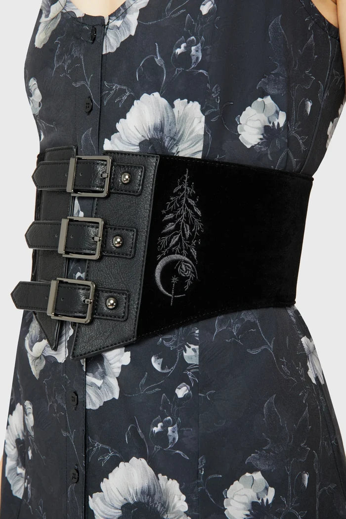 Model wearing a floral pattern dress with black corset-style belt on top