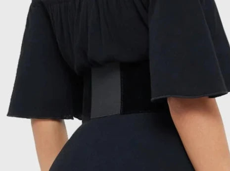 Model wearing a black dress with black corset-style belt on top