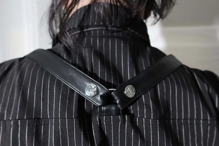 Model wearing a black and white pinstripe tip with tattoos on arms against a white background