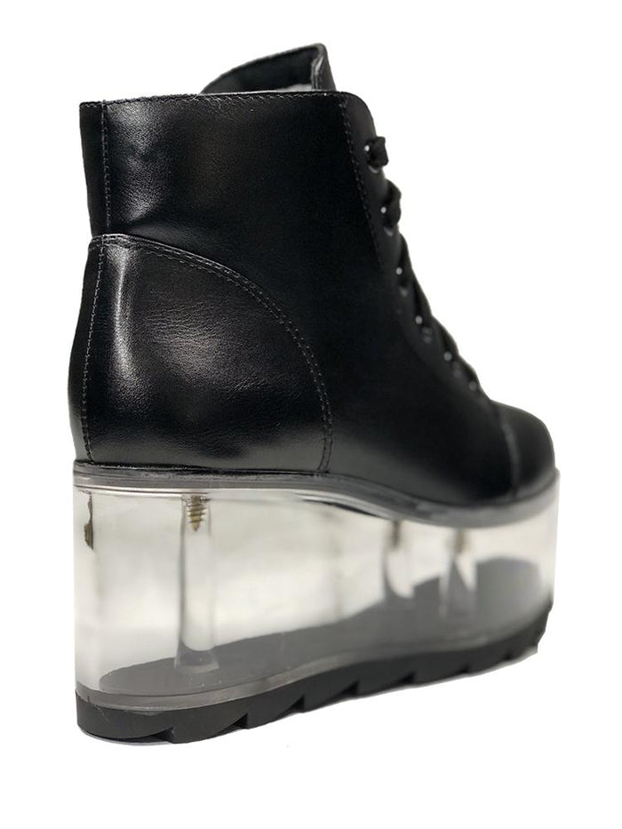 back view of black vegan leather platform shoe with clear plastic platform. Shoe looks like a sneaker, but is super tall! Clear plastic bottom has a Velcro foot bed opening, to insert toys, candy or fun stuff into the clear bottom of the shoe.