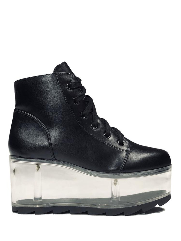 outer view of black vegan leather platform shoe with clear plastic platform. Shoe looks like a sneaker, but is super tall! Clear plastic bottom has a Velcro foot bed opening, to insert toys, candy or fun stuff into the clear bottom of the shoe.