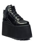 outer view of black vegan leather platform shoe with EVA platform. Shoe looks like a sneaker, but super tall! Shoe has nylon details and mesh lining. Bottom of platform has a "fanned" grip to make the platform more stable.