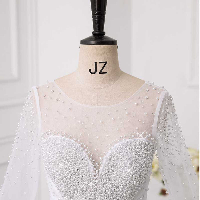 Elegant sweetheart tulle wedding dress with pearl detailing and long sheer sleeves