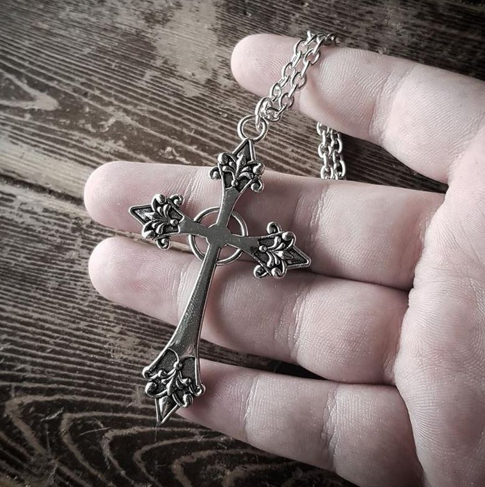 back side of Silver colored zinc alloy vampire cross necklace with red cubic zirconia gem in center of cross.