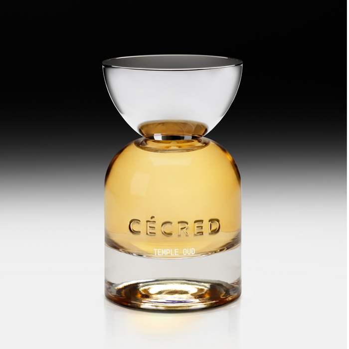 Clear glass bottle with gold-toned liquid, clear dome cap, and "CÉCRED" and "TEMPLE OUD" text on label.