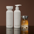 Two white cylindrical bottles labeled hydrating shampoo and conditioner with a golden fragrance bottle featuring a silver cap