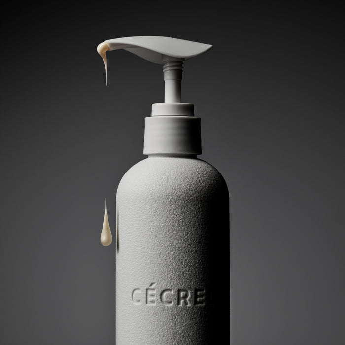 White textured pump bottle labeled "CÉCRE" with dispensing product droplets visible against dark background.