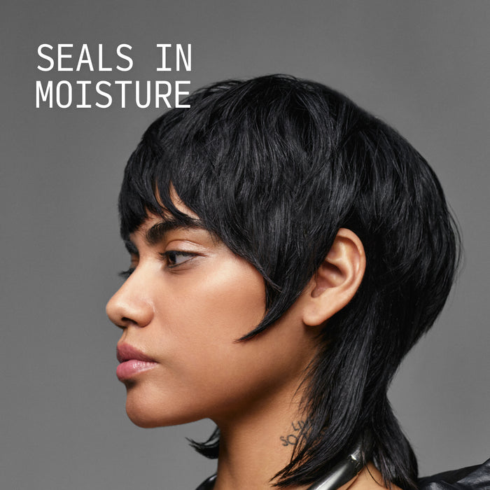 Model with glossy dark mullet-style cut showcasing Cécred Nourishing Hair Oil with Seals in Moisture text overlay against a grey background