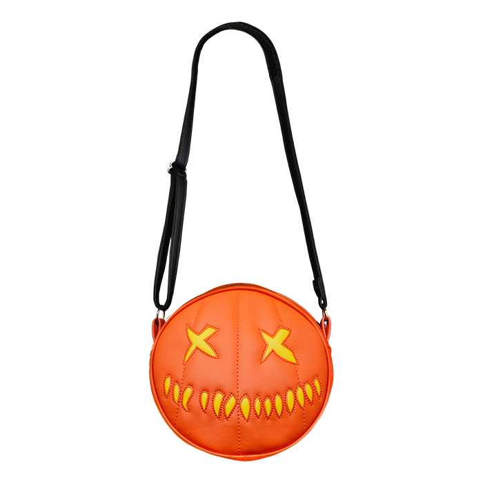 woman wearing bag on shoulder. bag is orange with yellow eyes and yellow teeth, with a black adjustable strap. based on sam's jack o lantern in the movie trick r' treat