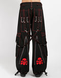 Black classic fit Tripp pants with red stitching, zipper details, removable straps on the back, drawstrings near the feet to tighten the fit, and red skulls printed on the back of each leg.